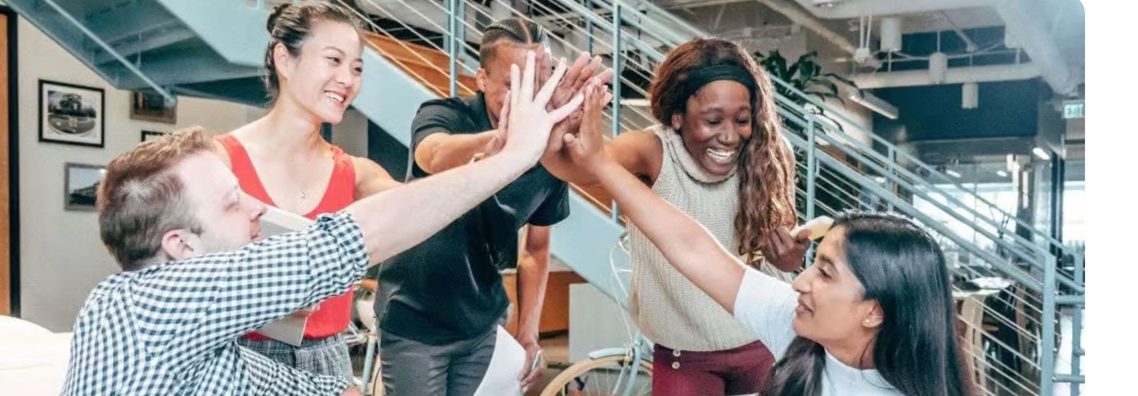 Diverse team mid-celebration, hands meeting in a high-five above the table